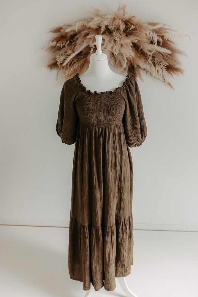 Auf dem Bild sieht man ein grünes Kleid, getragen von einer Schaufensterpuppe und Pampasgras im Hintergrund