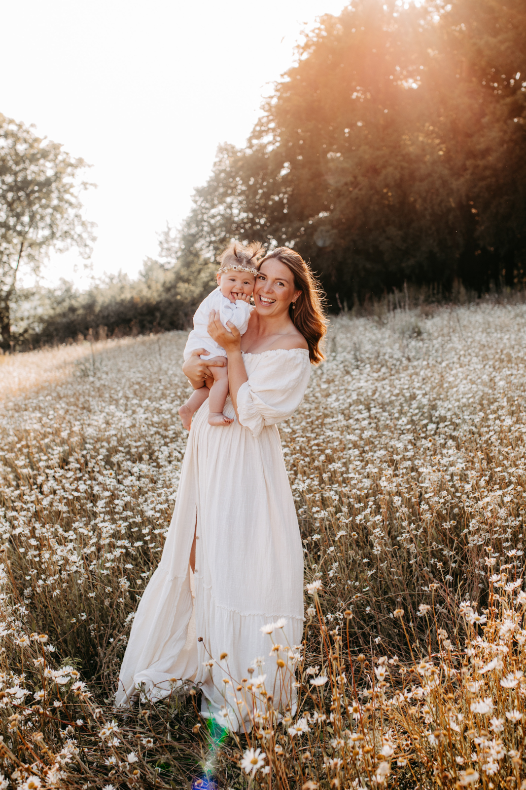 Familienshooting Calw. Auf dem Bild sieht man eine Frau mit Baby auf dem Arm. Sie stehen auf einer Blumenwiese